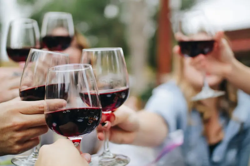 Grupo de personas brindando con copas de vino tinto