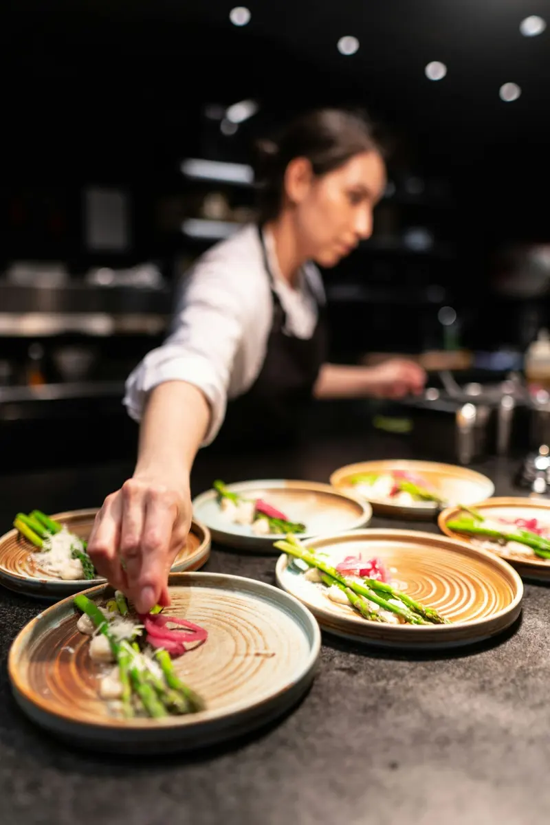 Cocinera decorando platos con espárragos antes de servirlos
