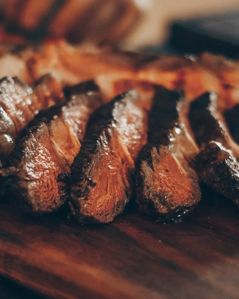 Carne asada cortada en lonjas sobre tabla de madera