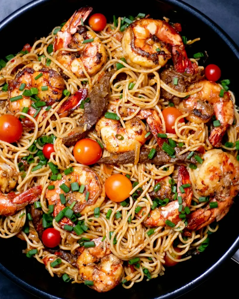 Espaguetis con camarones y tomates cherry en sartén negra